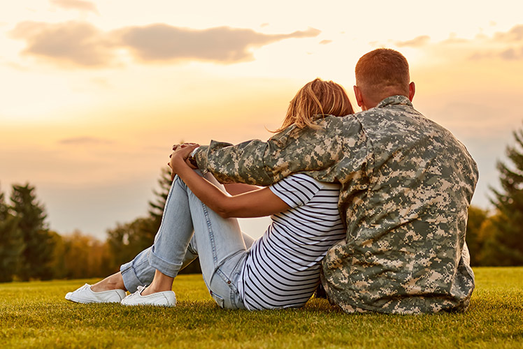 A soldier sitting with significant other watching the sunset.