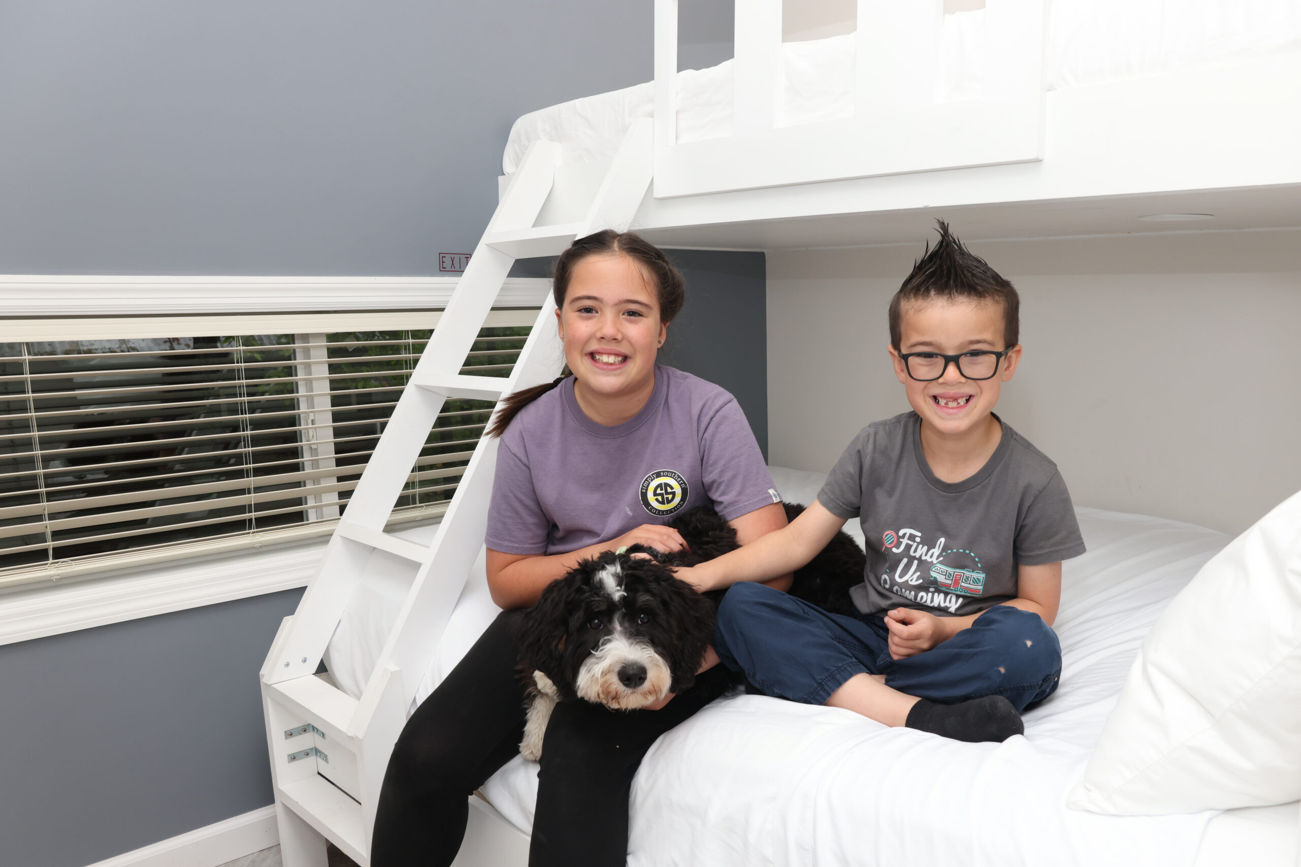 Kids sitting on a bunk bed with a dog